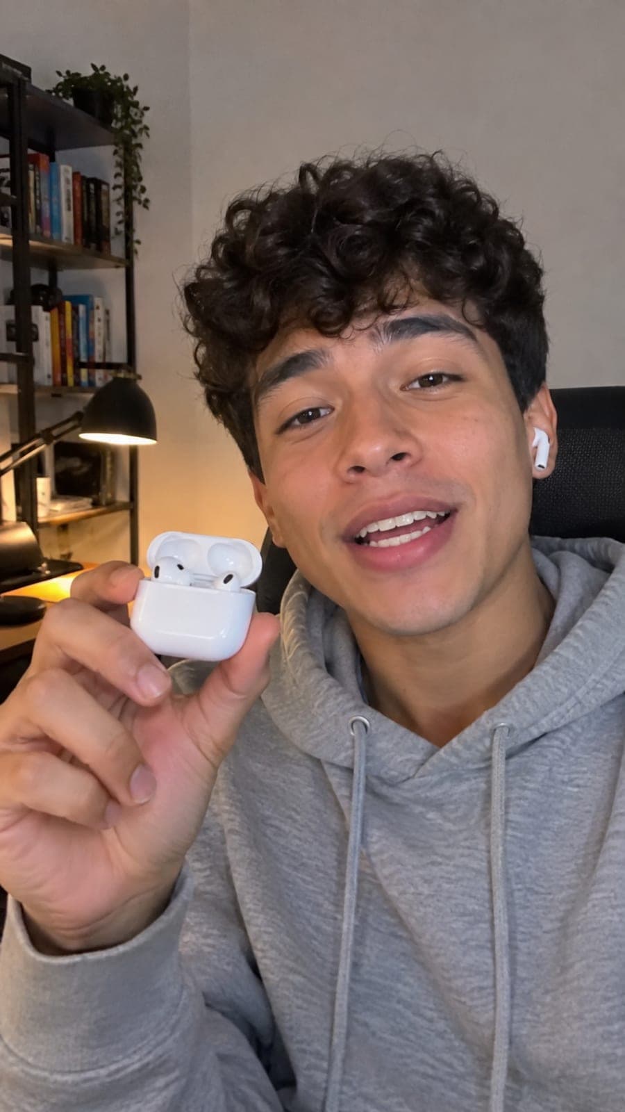Joven colombiano mostrando el estuche abierto de unos audífonos inalámbricos